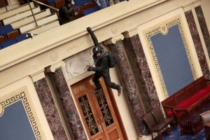 An extremist hangs from the balcony of the Senate chambers.